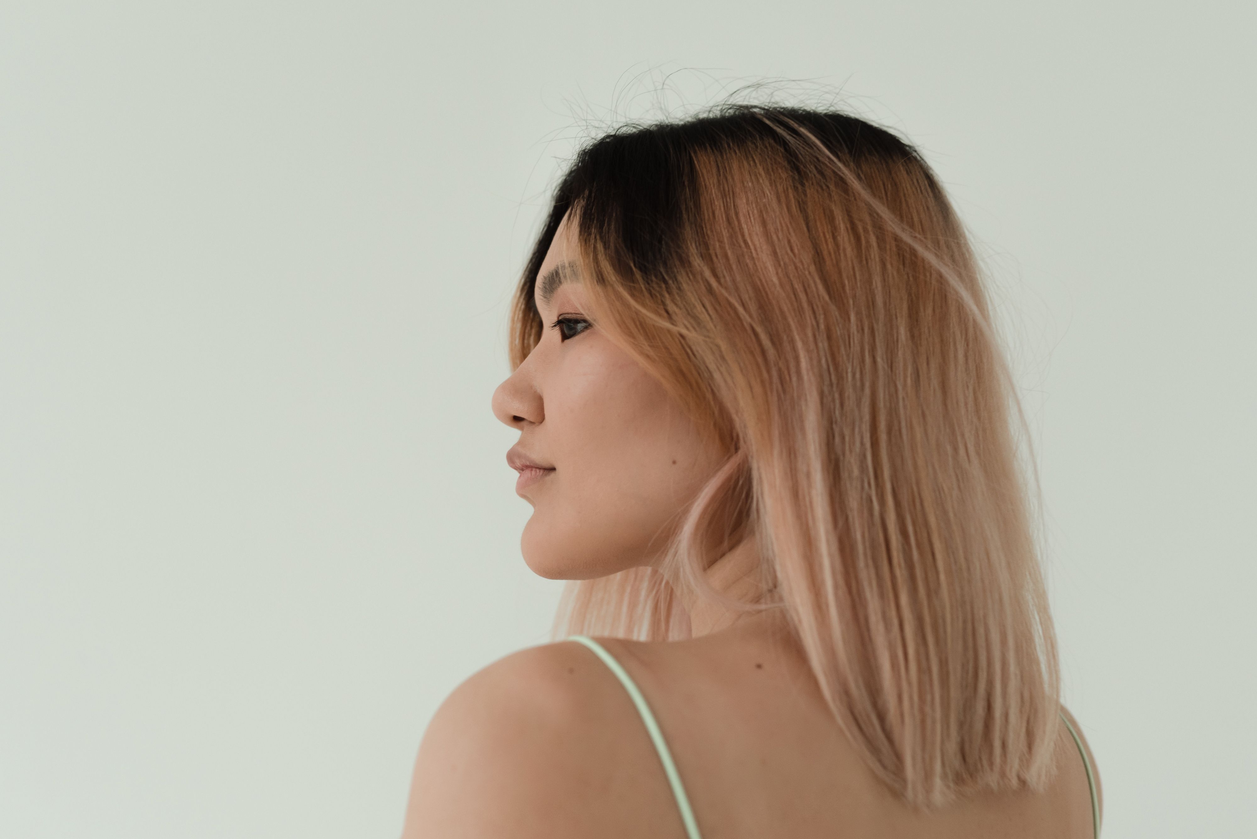 Side portrait of a woman with light pink balayage hair showing a blended multi-tone shade