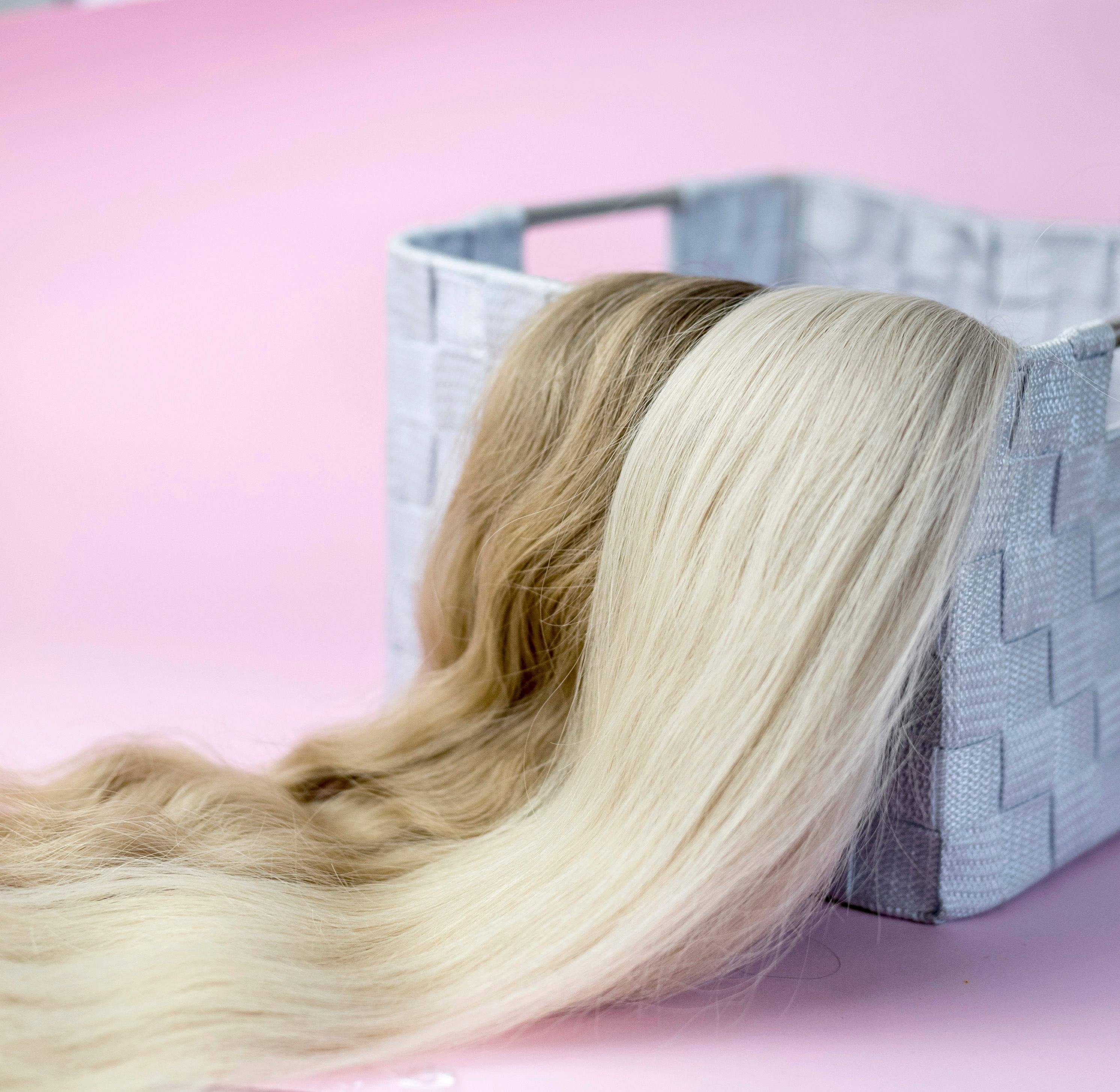 Blond and brown hair extensions in different shades displayed over a woven basket