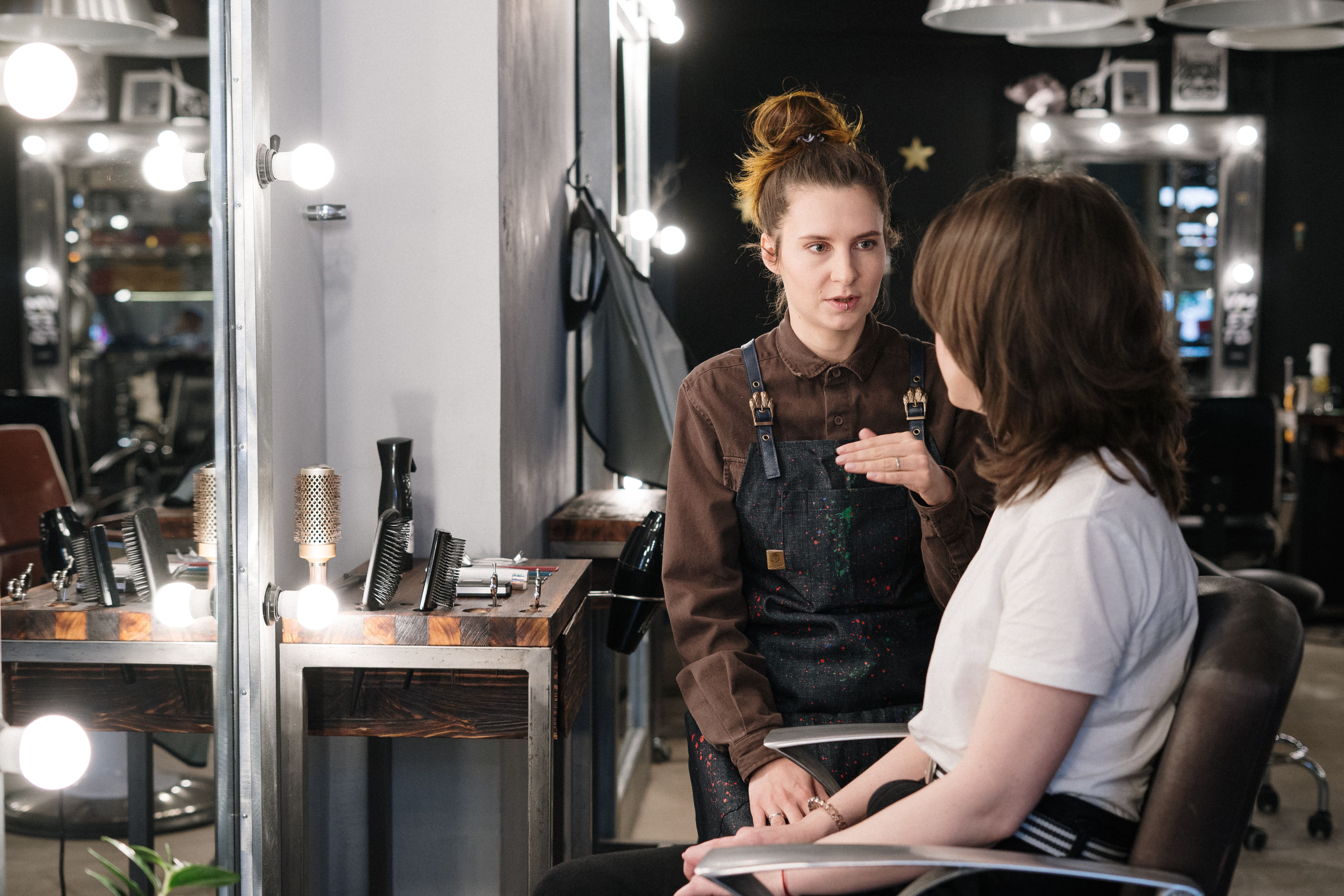 Hair stylist consulting a client about hair color and extension shade selection in a salon